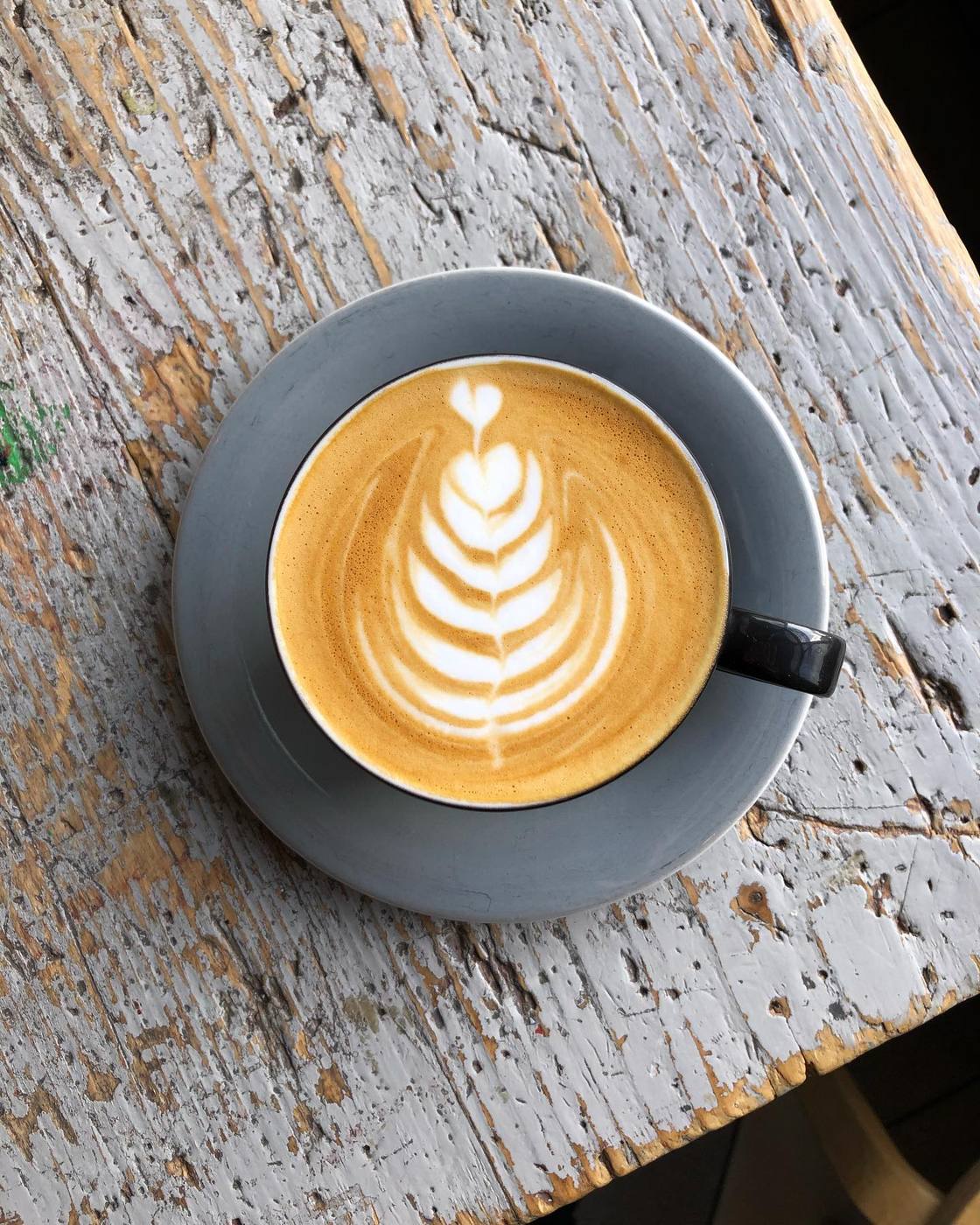 Latte with rosetta art on a weathered wooden table