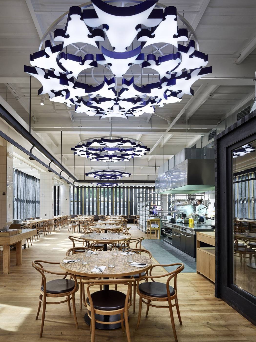 Čestr's dining room with bentwood chairs, sculptural ceiling lights and the open kitchen