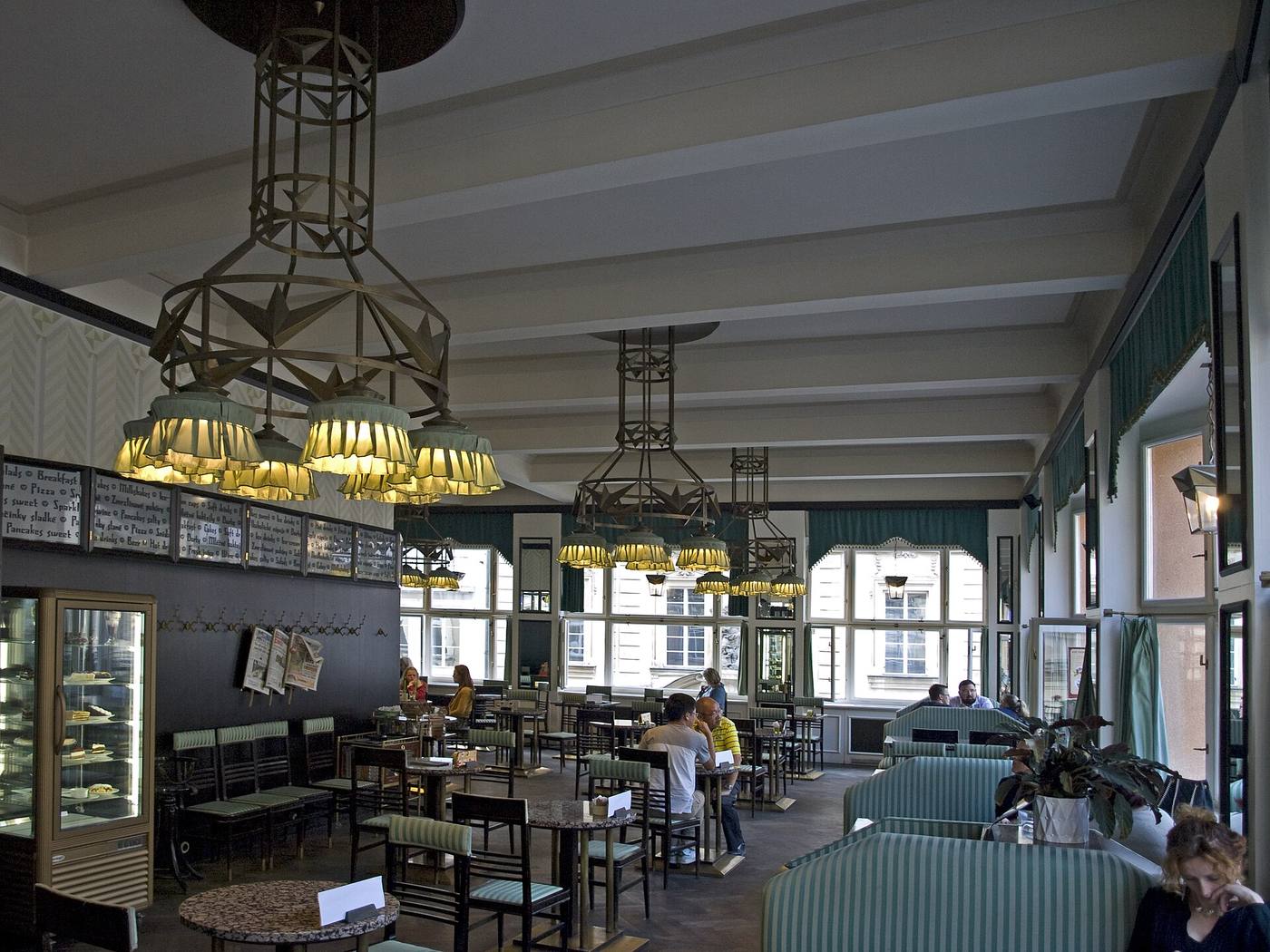 Interior of Grand Café Orient with cubist brass chandeliers and green upholstered seating