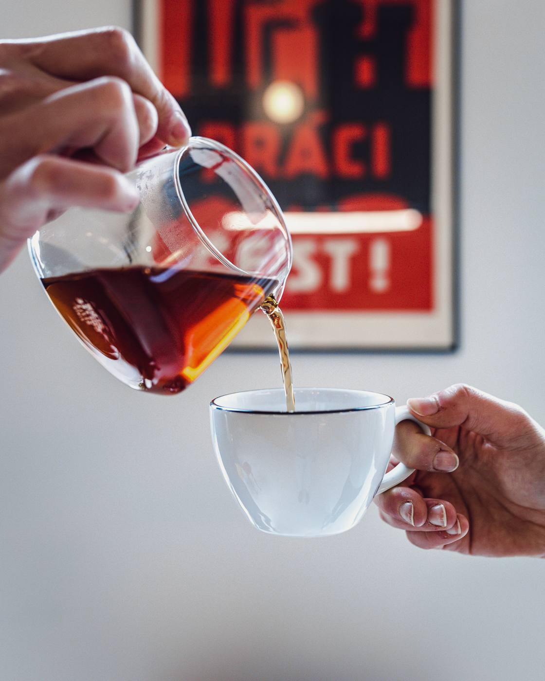 Filter coffee being poured from a glass carafe into a white cup