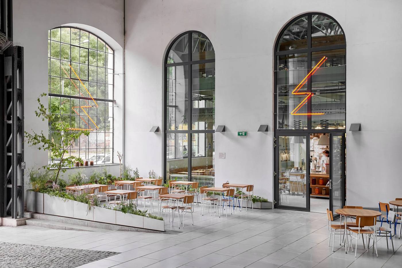 Tall arched windows and seating in the Eska Karlín hall