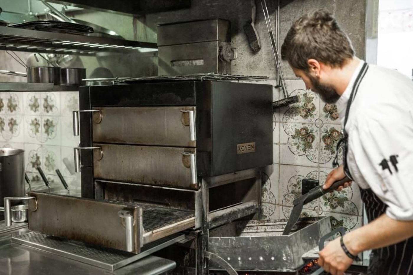 A chef working at the charcoal X-Oven in the La Bottega Linka kitchen