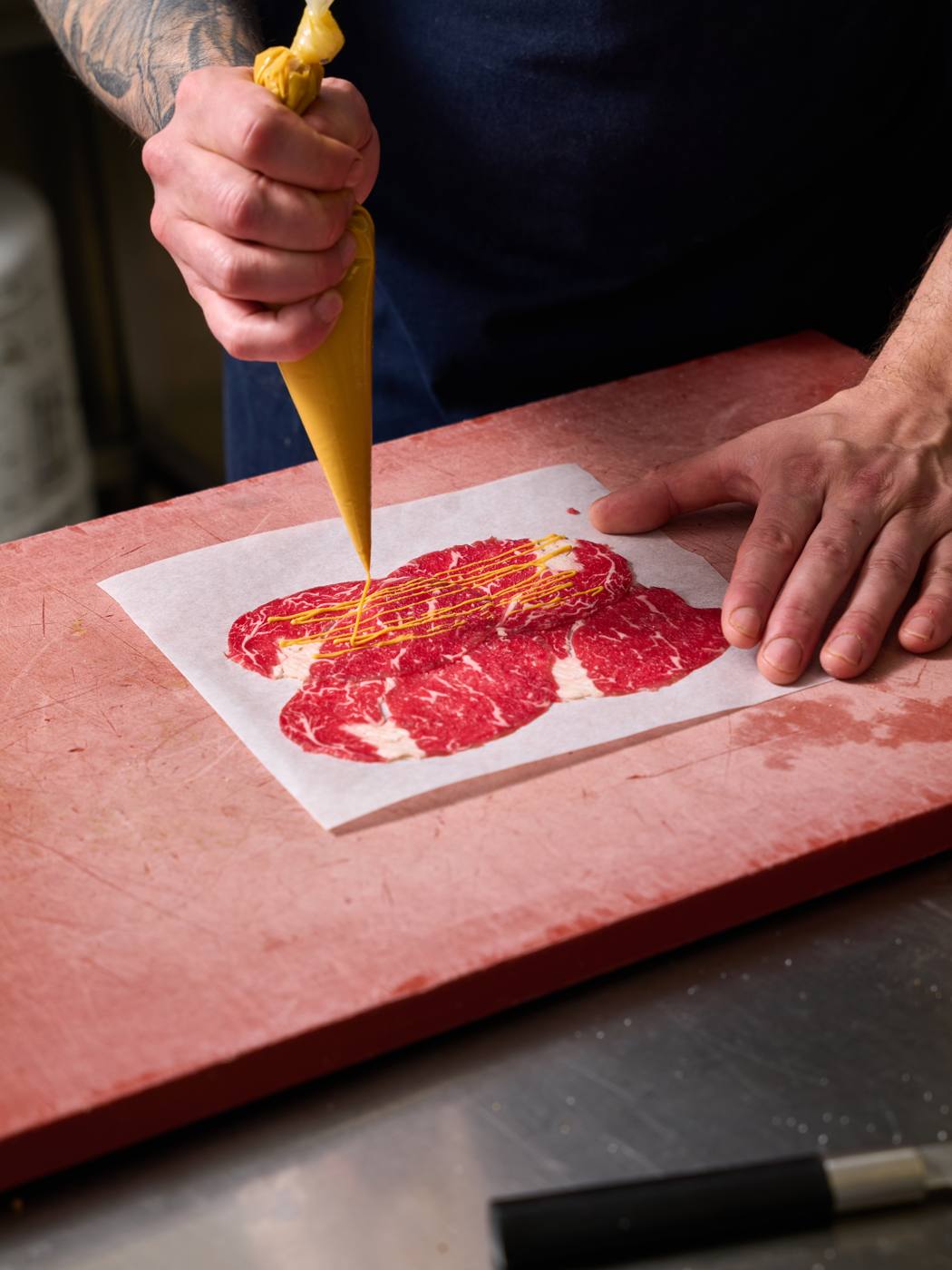 Beef carpaccio being sauced at La Degustation