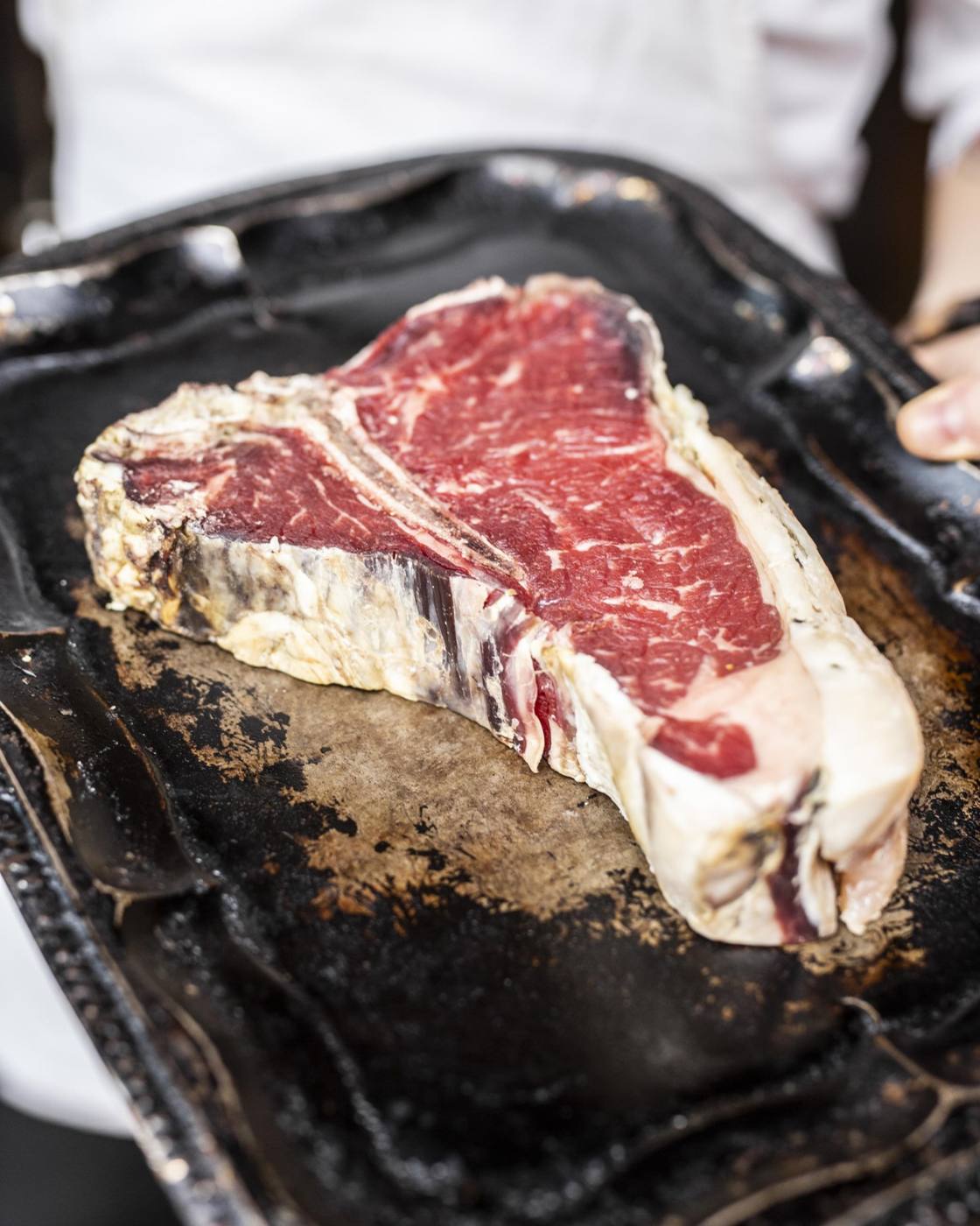 Thick raw dry-aged T-bone steak on a tray