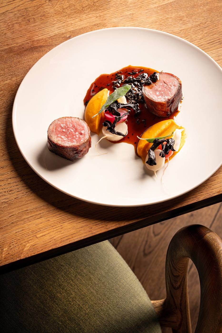 Plated grilled lamb loin with seasonal vegetables and jus