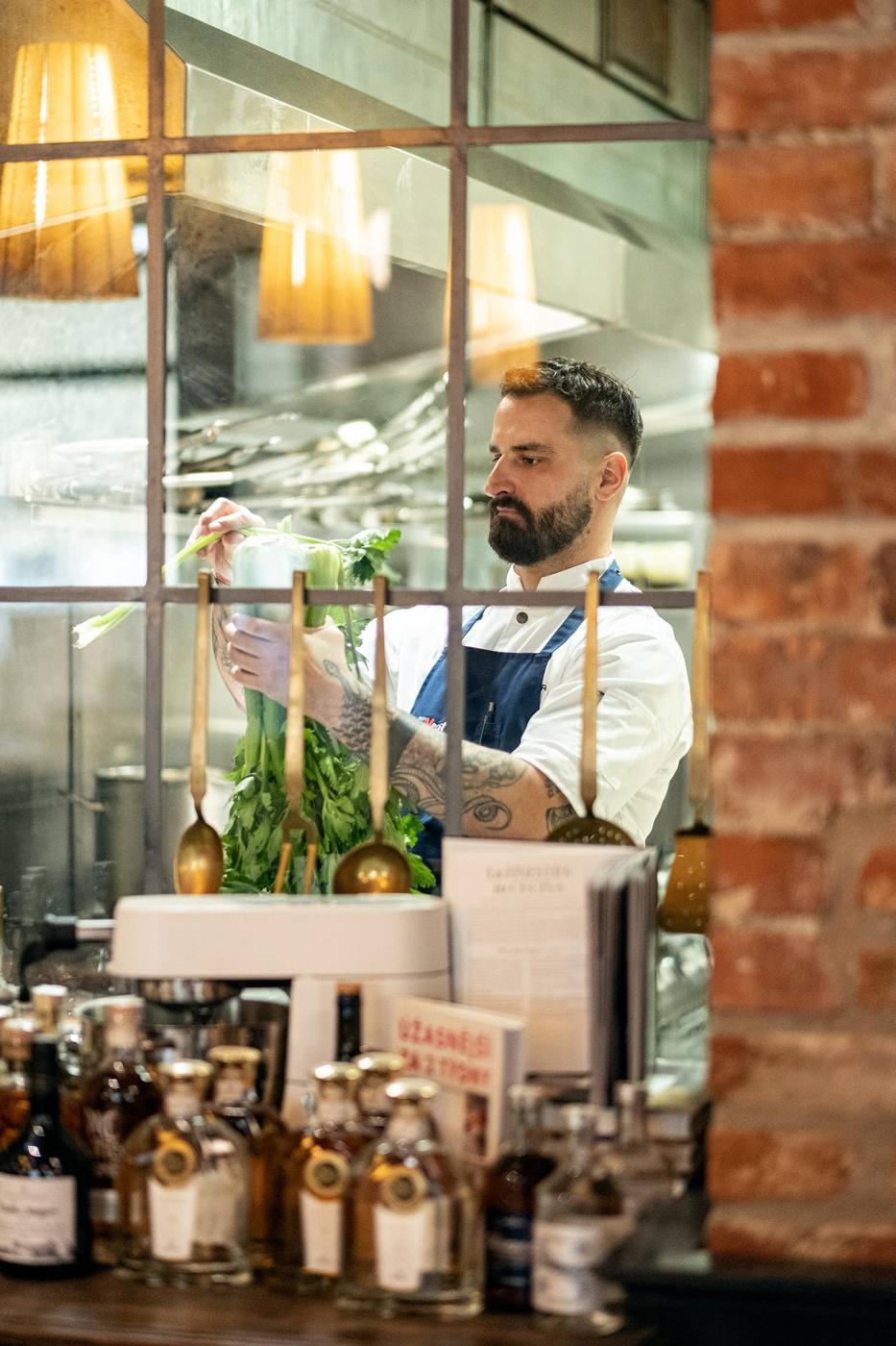 Chef working behind the glass kitchen window next to a red-brick wall