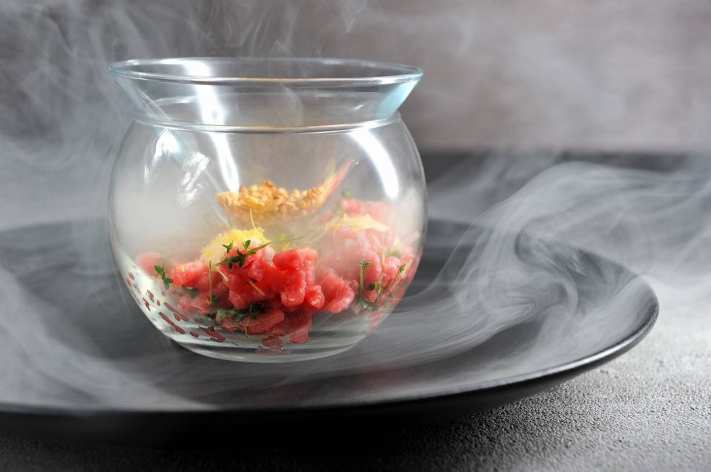 Tartare served under a smoke-filled glass bowl