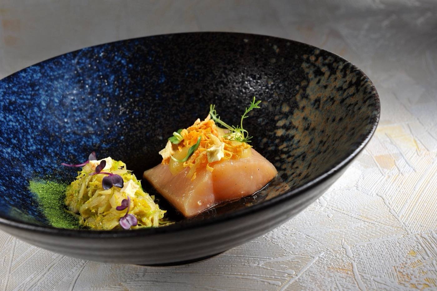 Fish fillet with herb purée in a dark blue ceramic bowl