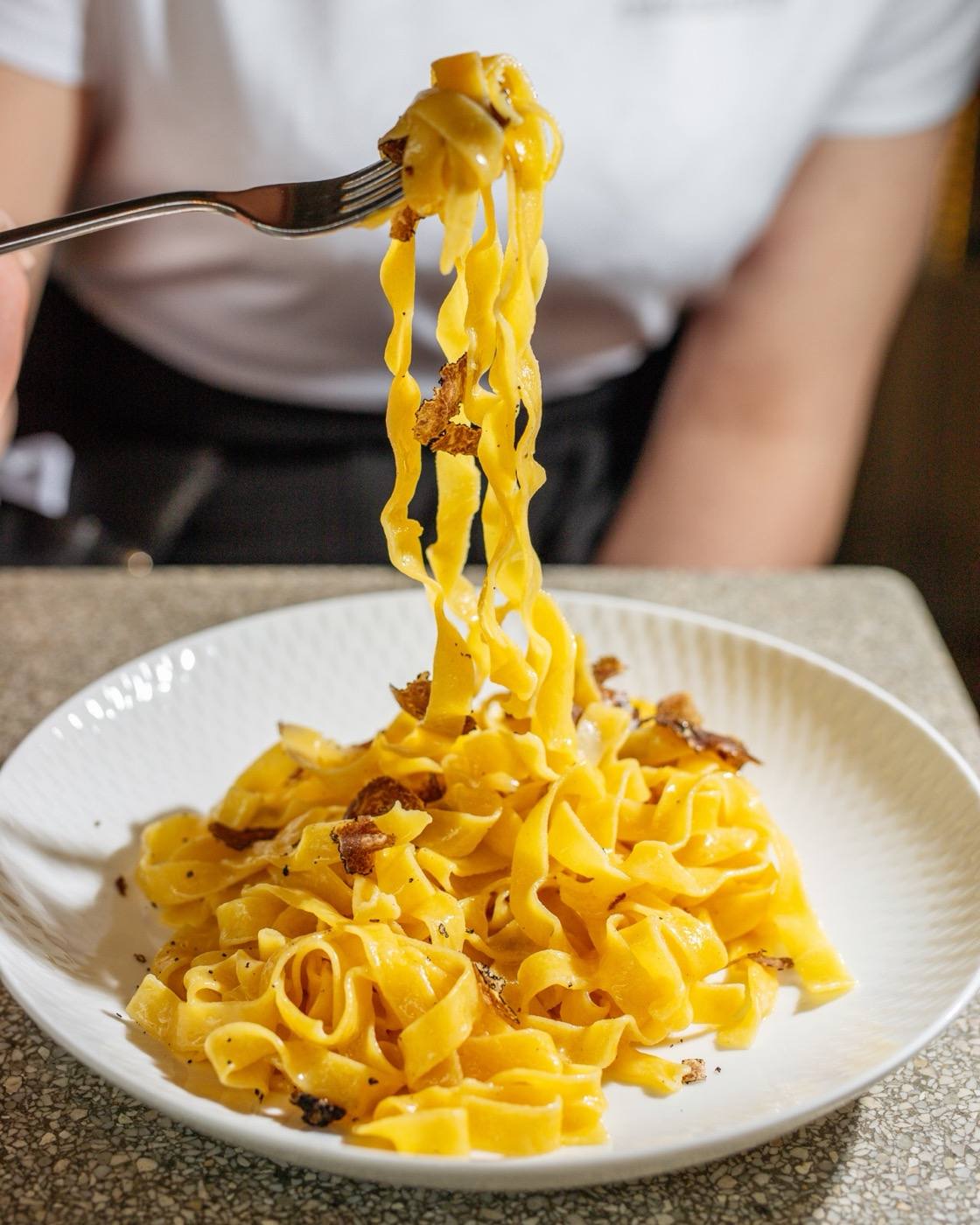 A forkful of fresh tagliatelle lifted from a white plate