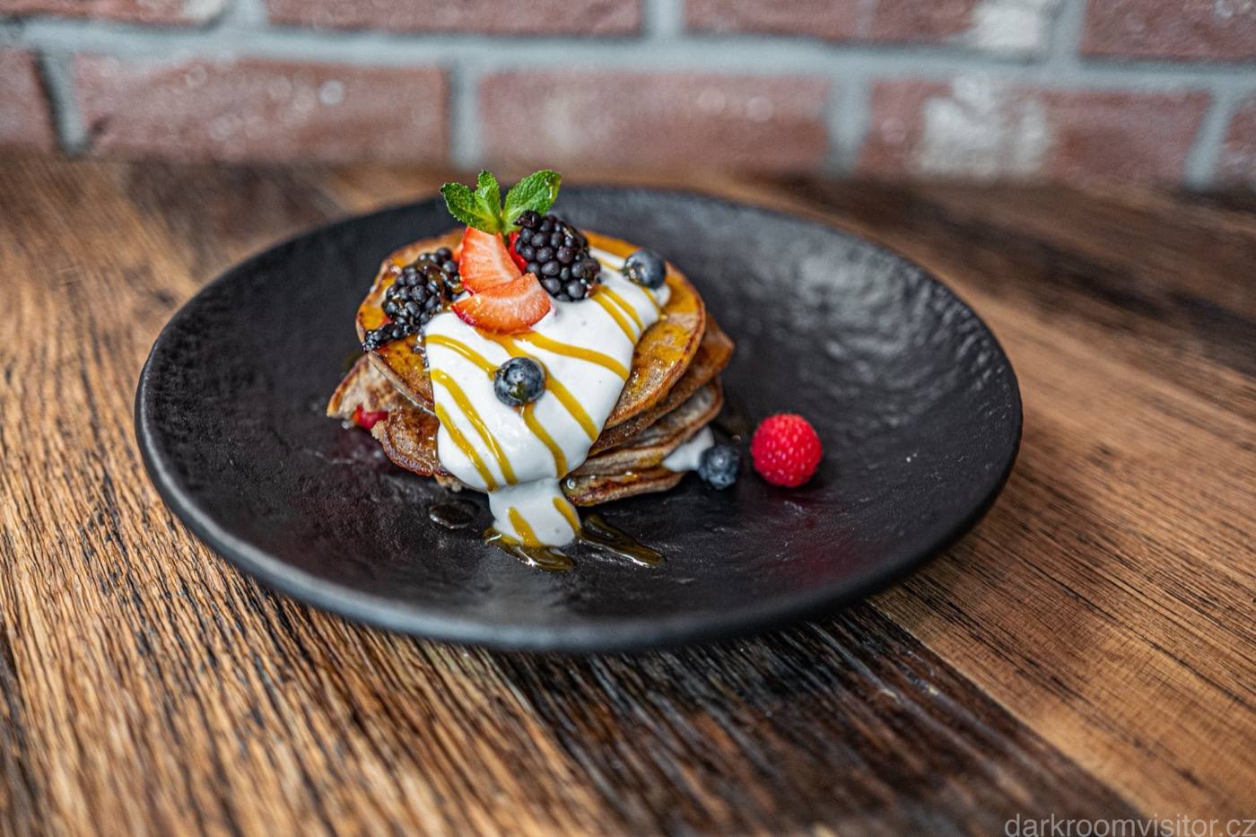 Stack of pancakes with berries and cream on a dark plate