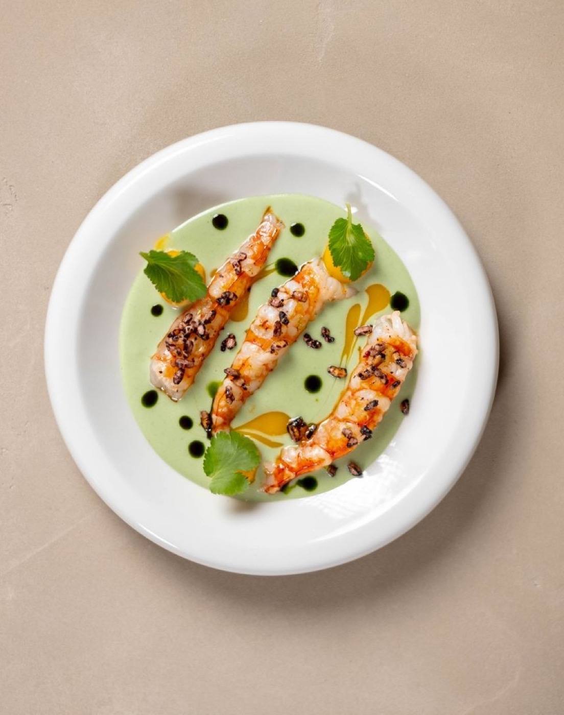 Prawns on a pale green wasabi sauce with mango, cilantro leaves and crispy black rice