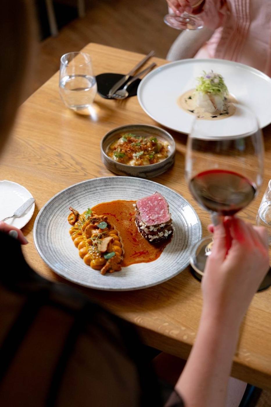 A table with seared beef, chanterelles and a glass of red wine at V Zátiší